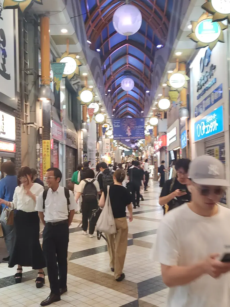 지붕이 덮인 상점가 아케이드. 저녁 인파가 오간다.