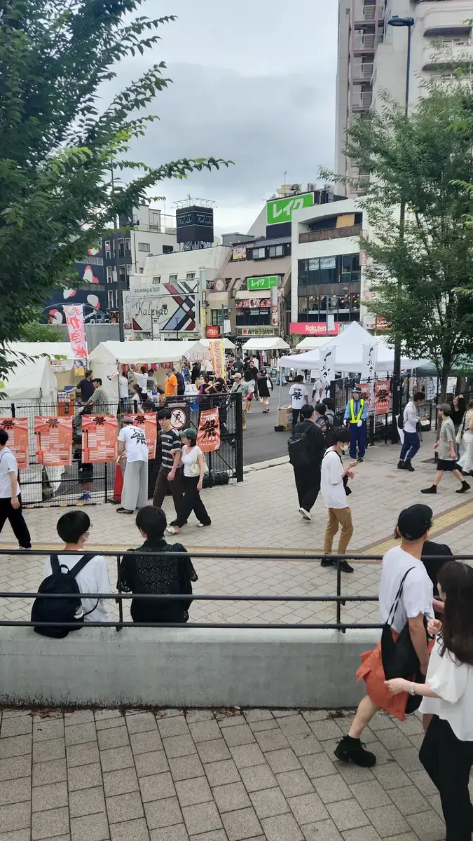 축제가 열린 거리. 사람들이 계단에 앉아 무대를 보고 있다.